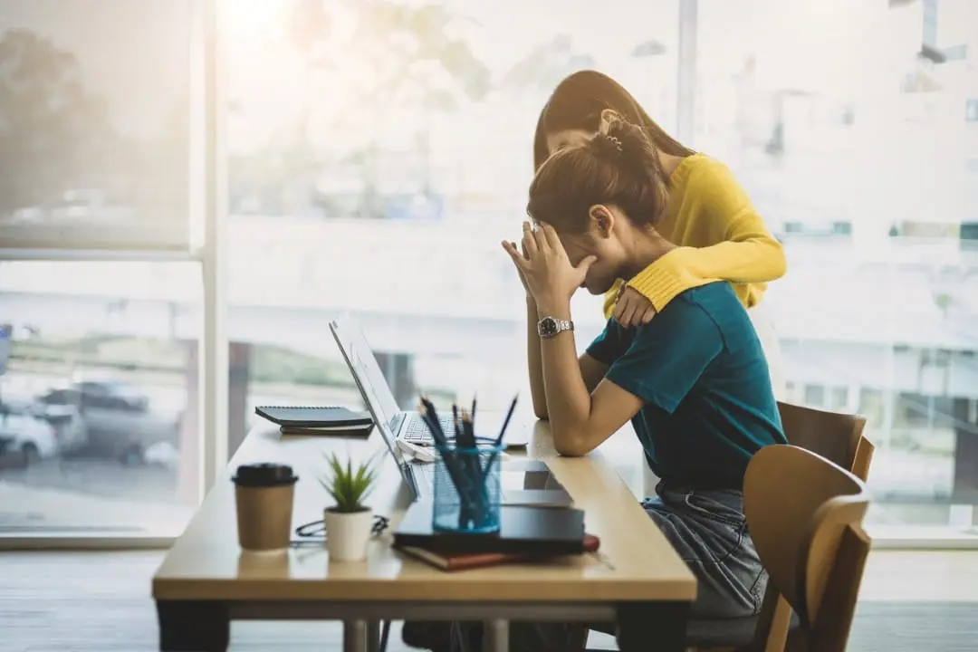 Colega de trabalho confortando mulher estressada