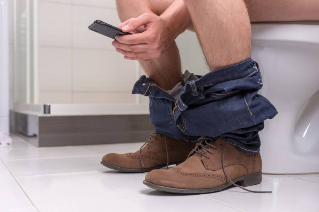 Homem sentado no vaso sanitário