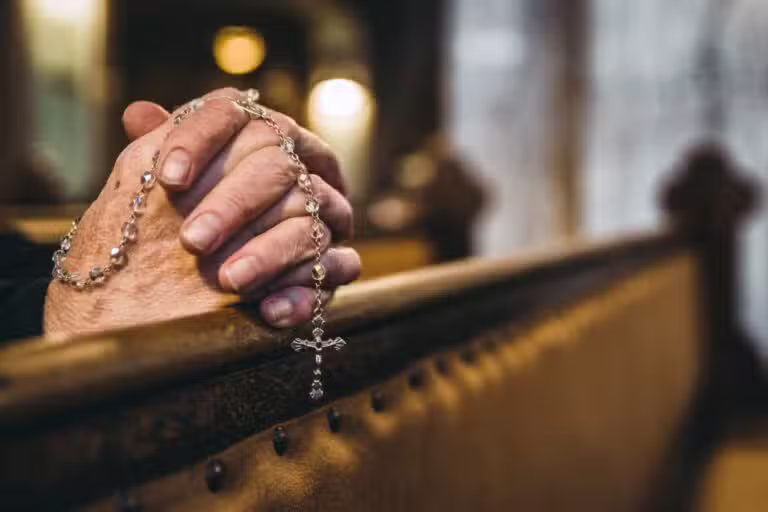 Mãos com o Rosário na igreja, católico, reza