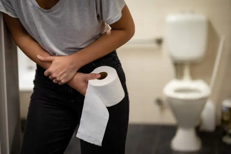 Vaso sanitário, mulher com papel higiênico na mao, dor