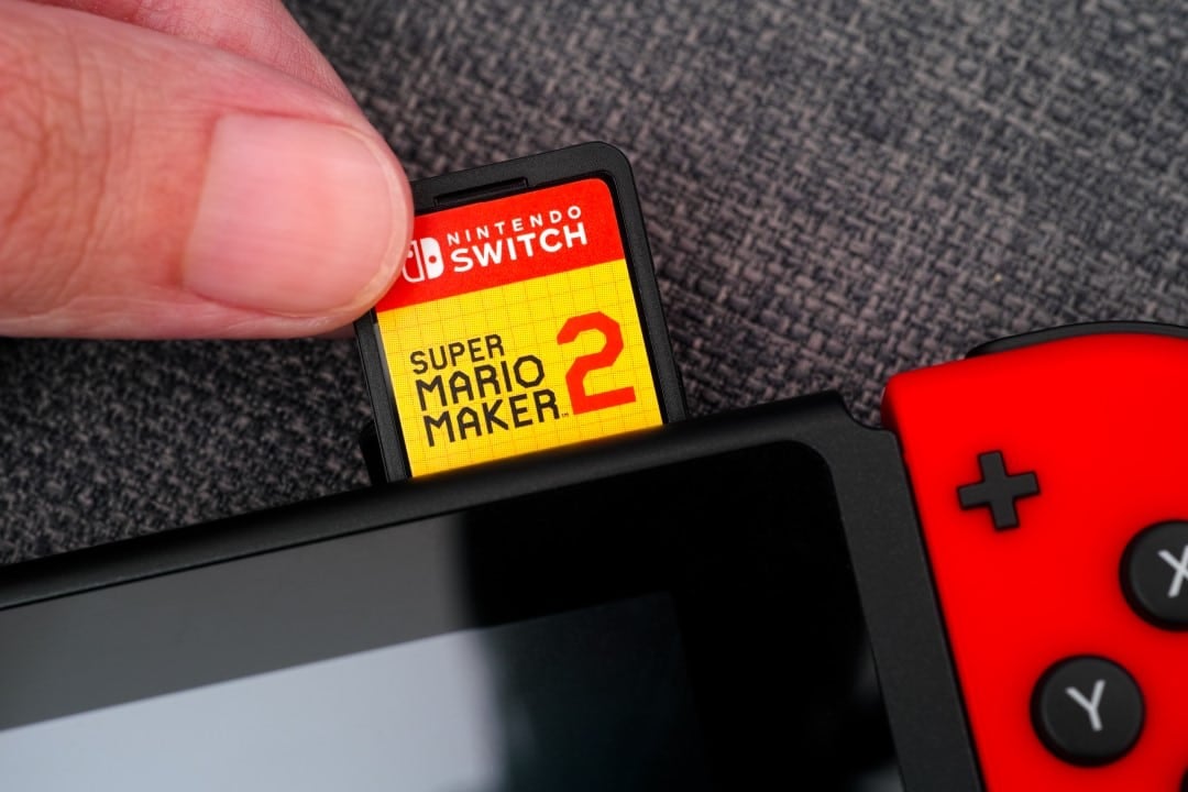 Dedos de pessoa inserindo cartucho de videogame Nintendo.