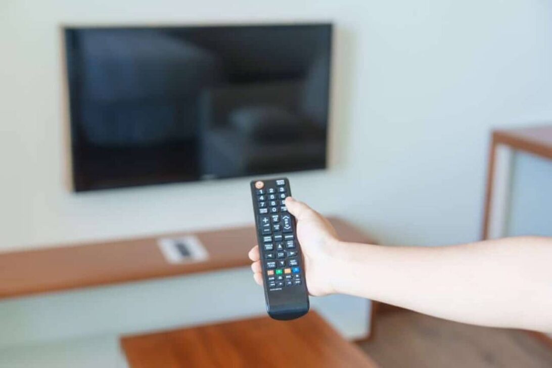 Mão usando controle remoto, televisão