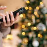 Mulher com telefone,. arvore de Natal ao fundo