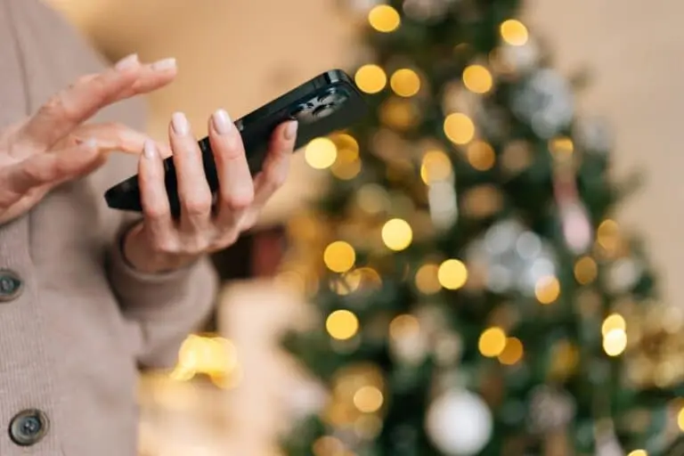 Mulher com telefone,. arvore de Natal ao fundo