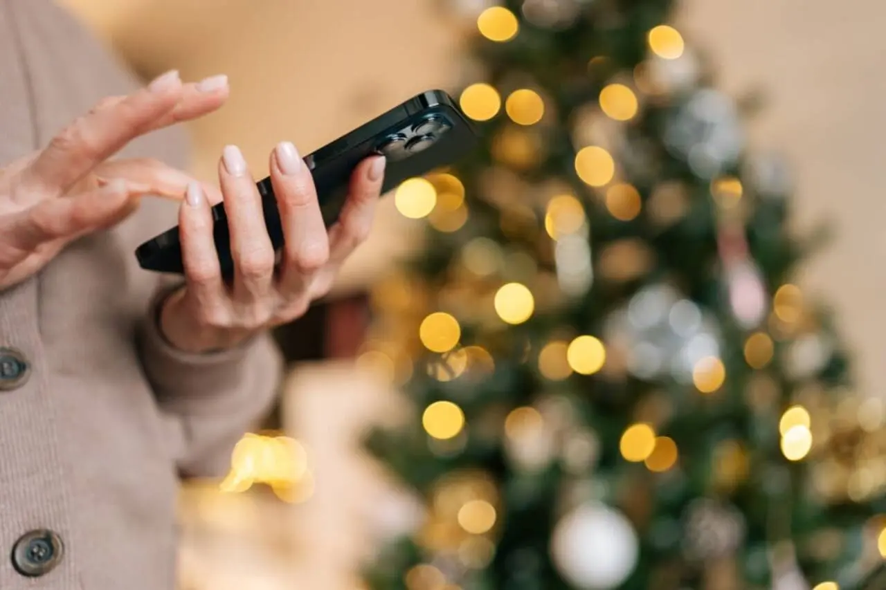 Mulher com telefone,. arvore de Natal ao fundo