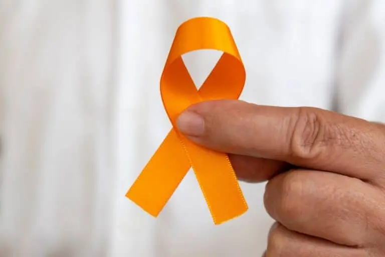 mão segurando uma fita laranja. campanha de prevenção ao câncer de pele