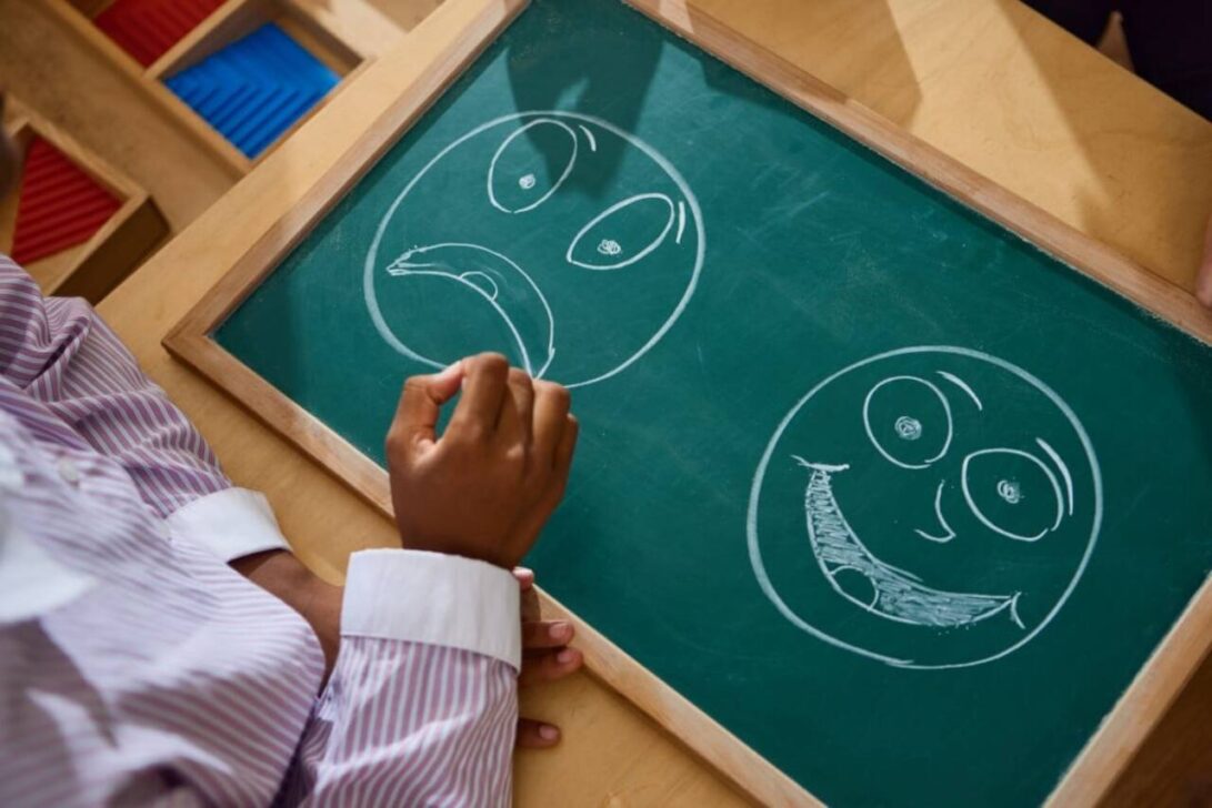 Criança apontando para quadro-negro com rostos emocionais, Conceito de psicologia infantil