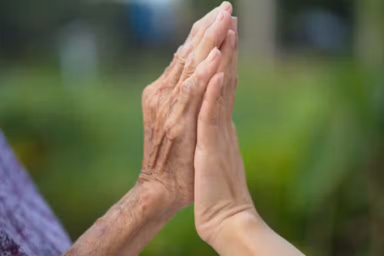 Mãos juntas, idosa e jovem