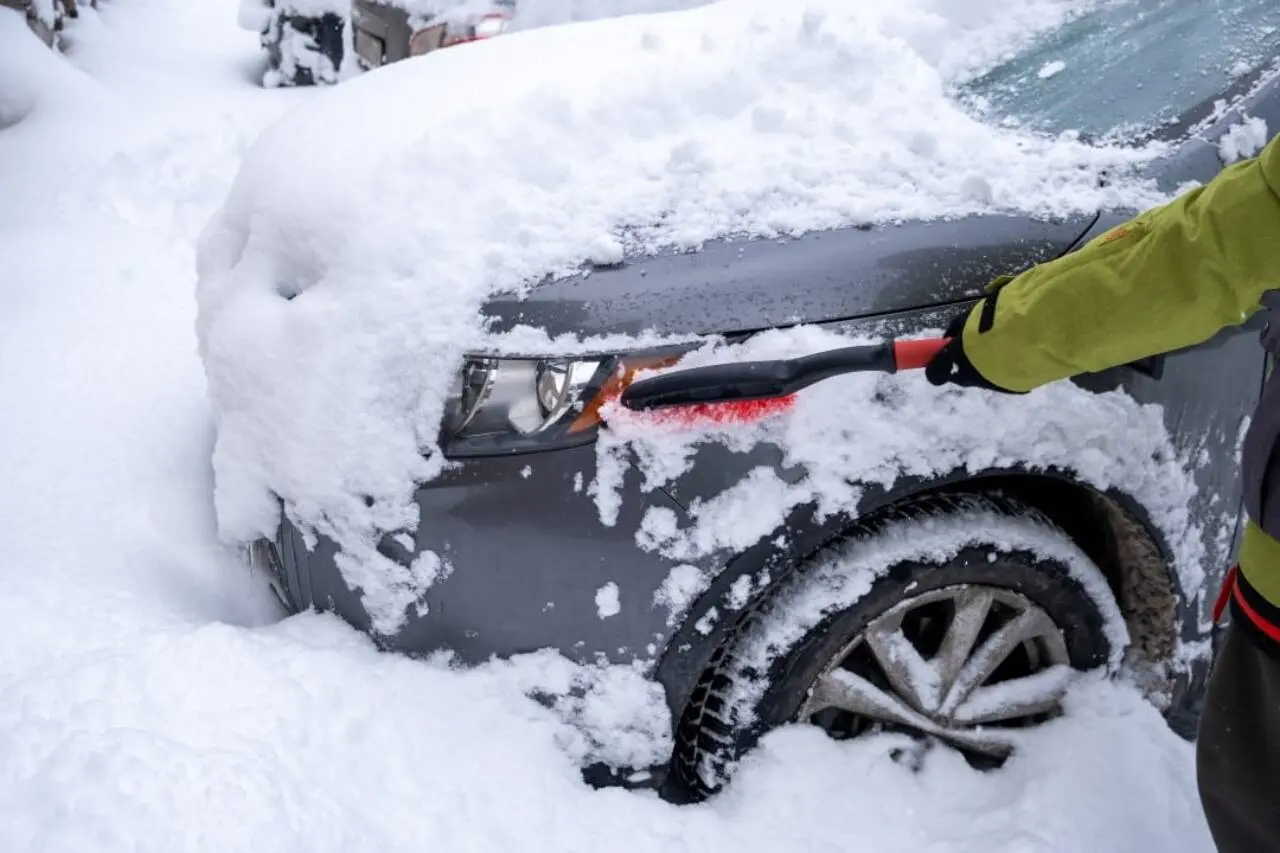 Neve no carro, pessoa removendo a neve do carro