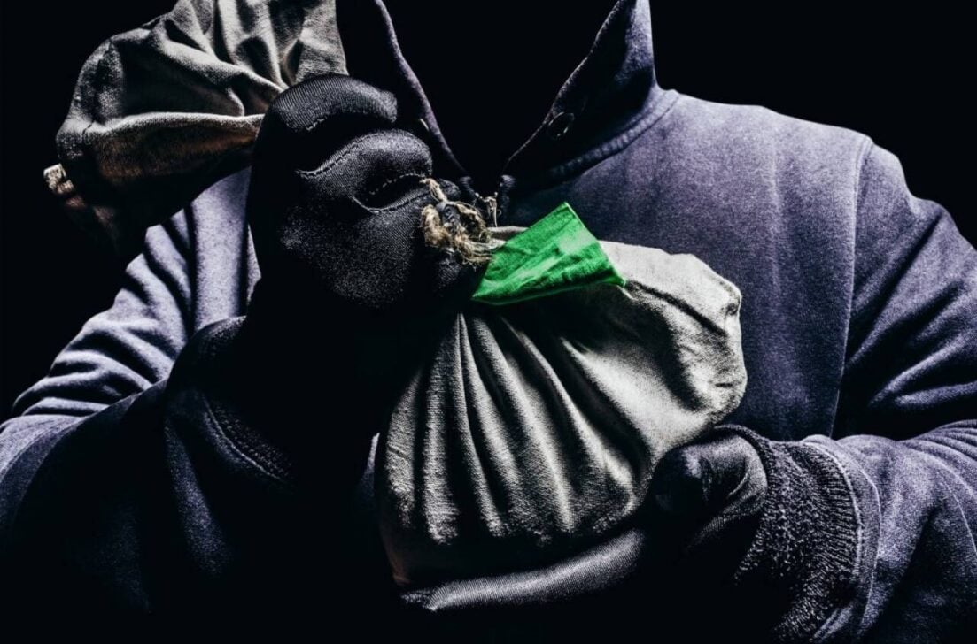 Foto de um homem encapuzado assustador segurando uma sacola, conceito de roubo