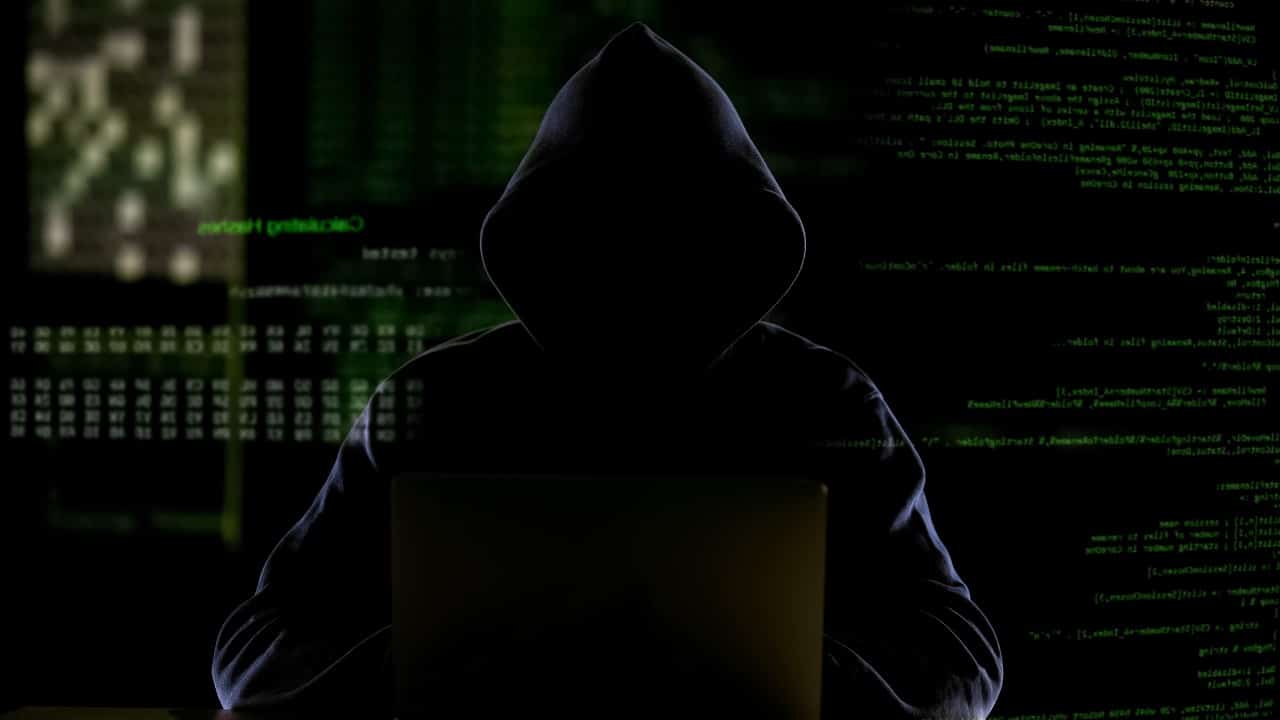 Homem encapuzado trabalhando com código de computador, hackeando software