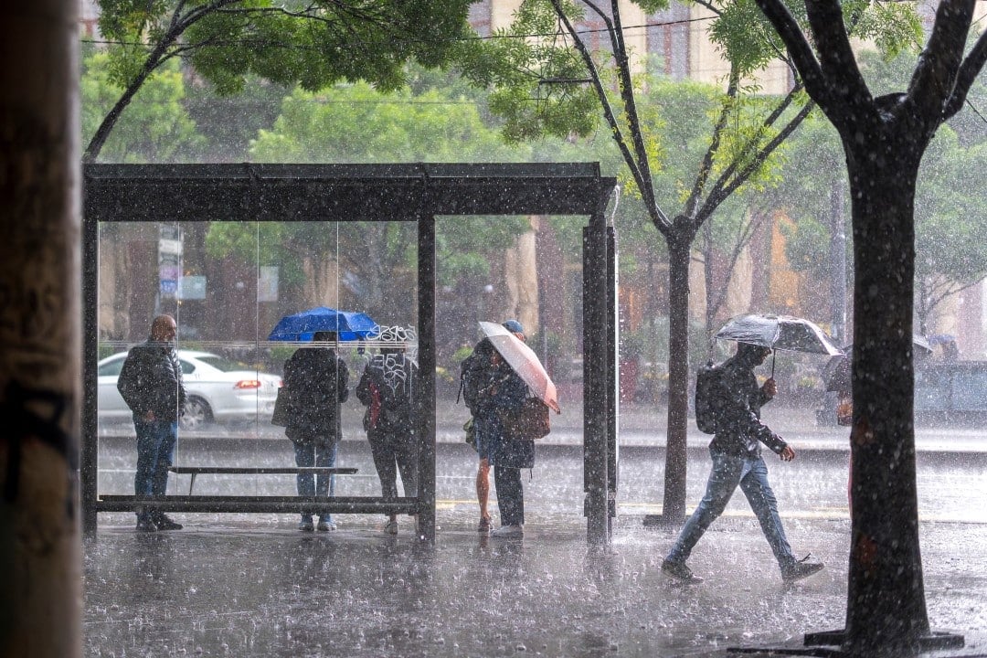 Pessoas em ponto de ônibus, chuva intensa, temporal