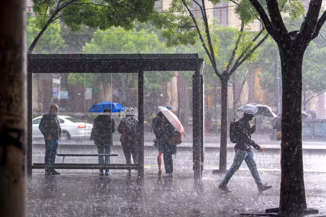 Pessoas em ponto de ônibus, chuva intensa, temporal
