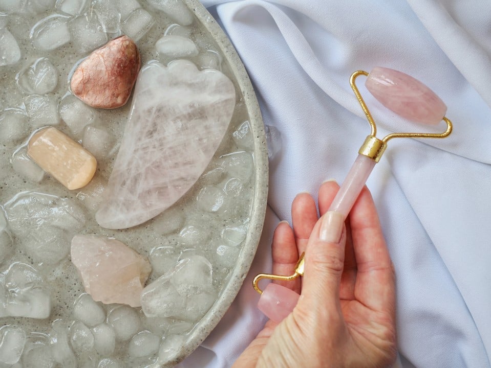 Rolo de massagem facial, gua sha, e pedras semipracious no gelo