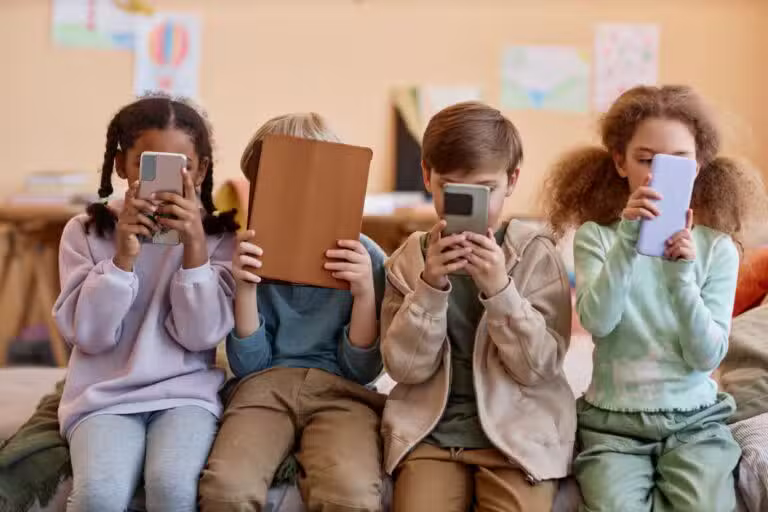 Grupo de crianças pequenas com celular nas mãos