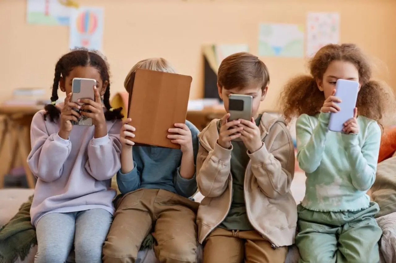 Grupo de crianças pequenas com celular nas mãos