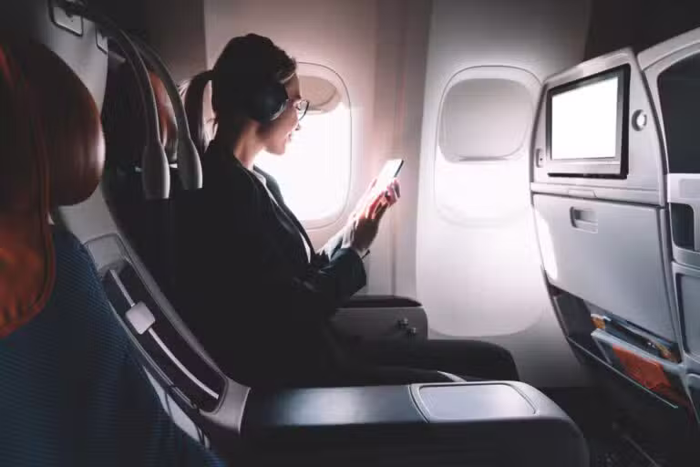 Mulher de fones e uso de telefone em avião