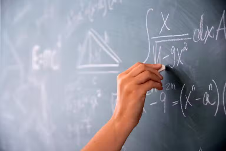 mão segurando giz, equações matemáticas no quadro, professor