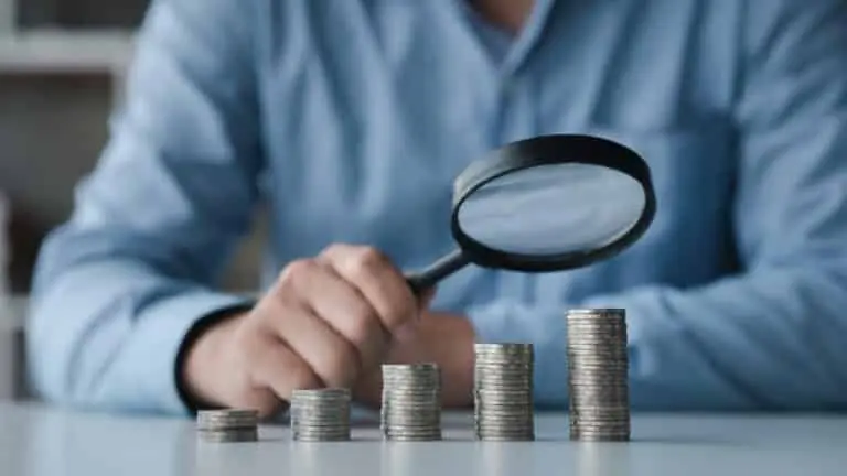 Pilhas de moedas, lupa, conceito de finanças