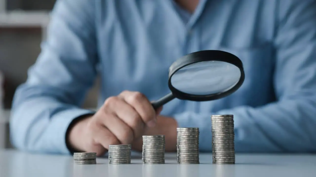Pilhas de monede, lupă, concept financiar