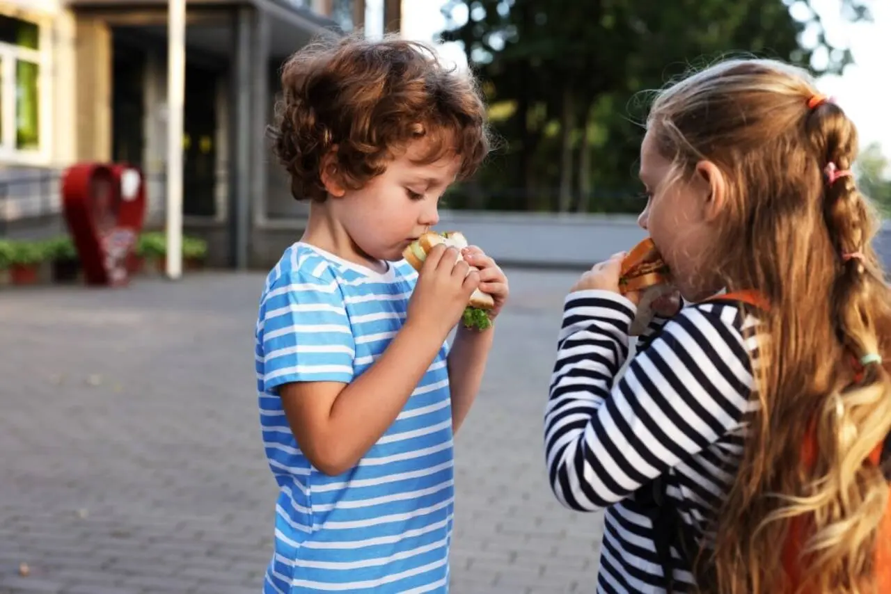 Crianças chicas guapas comiendo sándwiches, comiendo