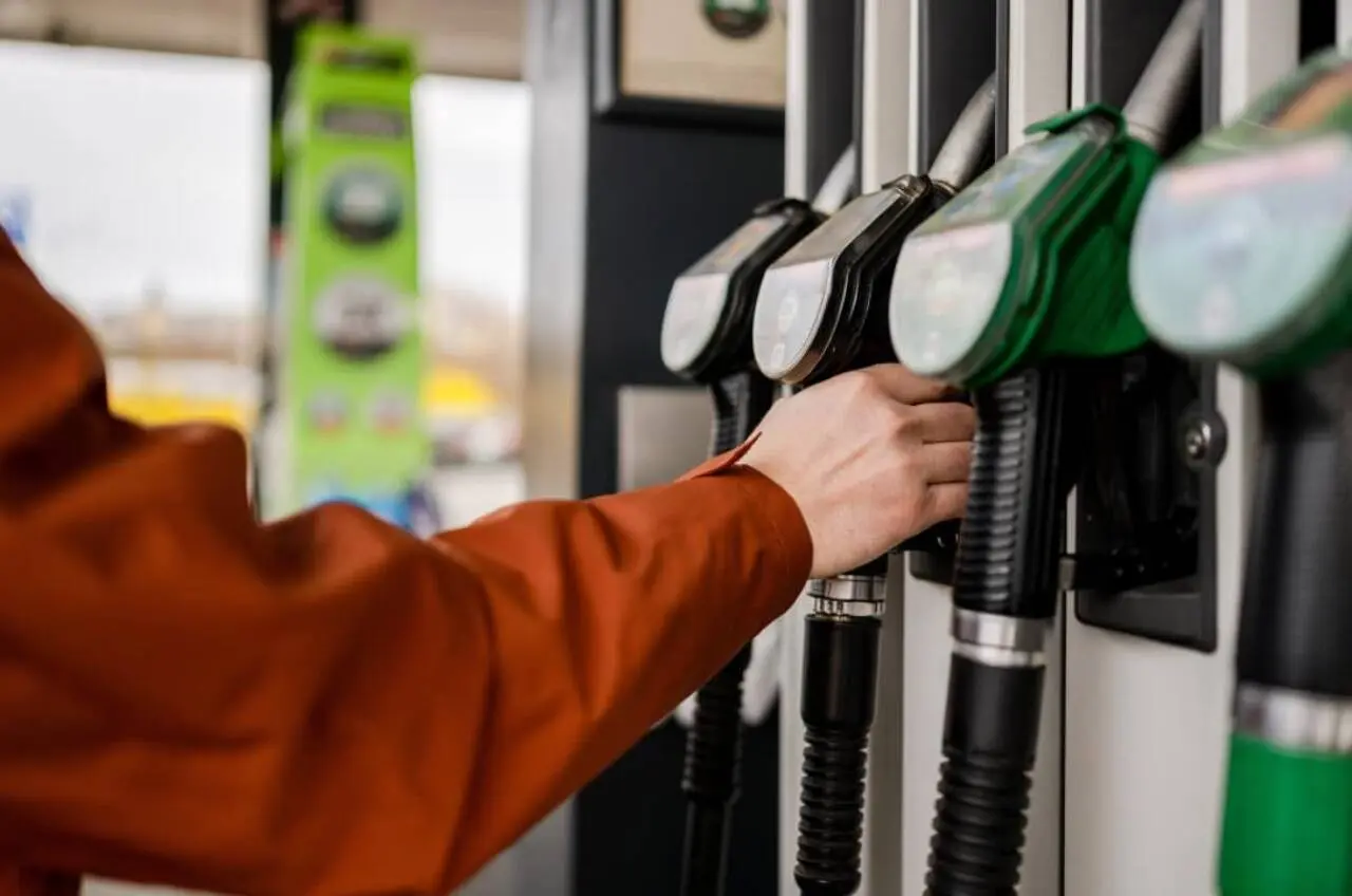 Homem agarrando uma bomba de combustível em um posto de gasolina
