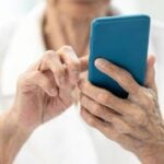 Mãos de idosa segurando telefone, celular