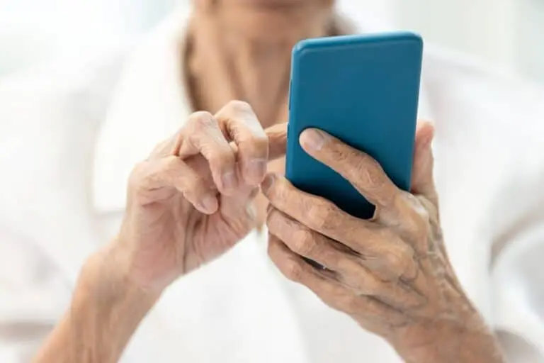 Mãos de idosa segurando telefone, celular