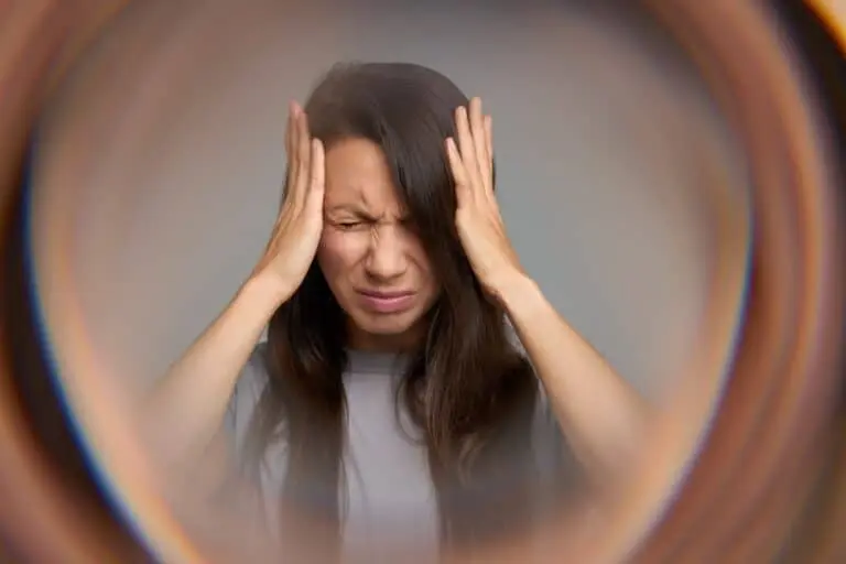 Mulher fechando os olhos com dor, aura por enxaqueca