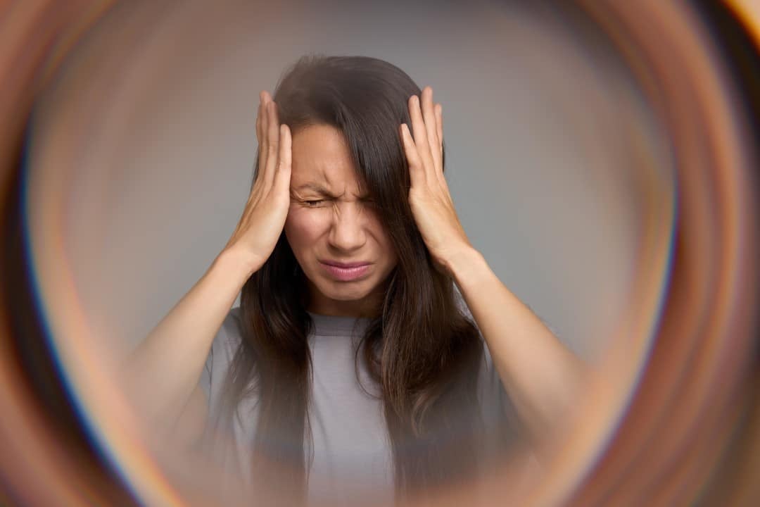 Mulher fechando os olhos com dor, aura por enxaqueca