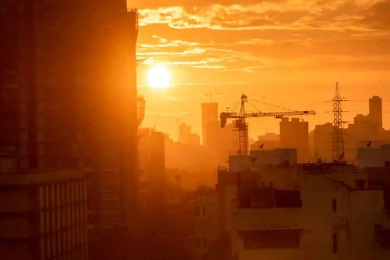 Silhueta de um guindaste e um edifício ao pôr do sol, calor