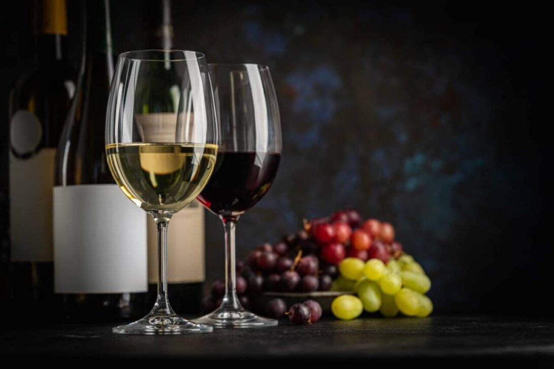 Vinho branco e tinto, garrafas de vinho e uvas