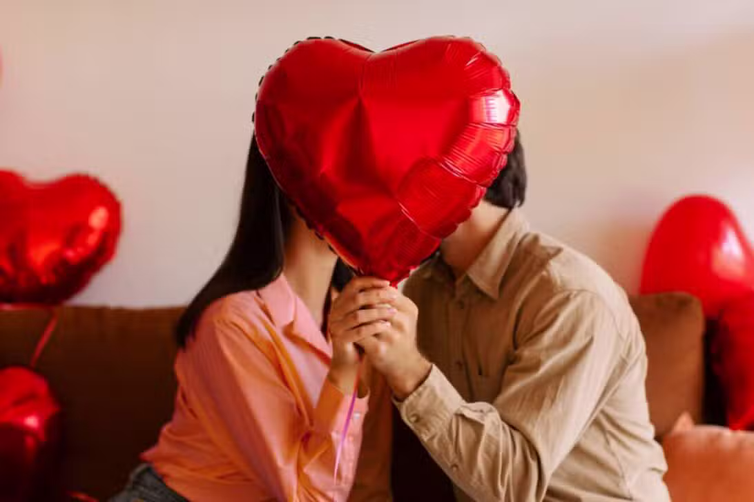 Casal beijando e segurando balão de coração, Dia dos Namorados
