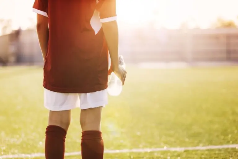 Jogador no campo de futebol, garrafa de água, hidratação