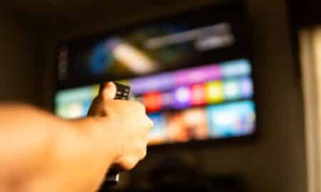Mão segurando controle remoto, streaming, smart tv