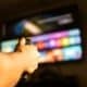 Mão segurando controle remoto, streaming, smart tv
