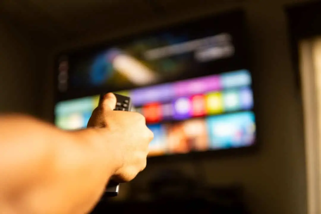 Mão segurando controle remoto, streaming, smart tv