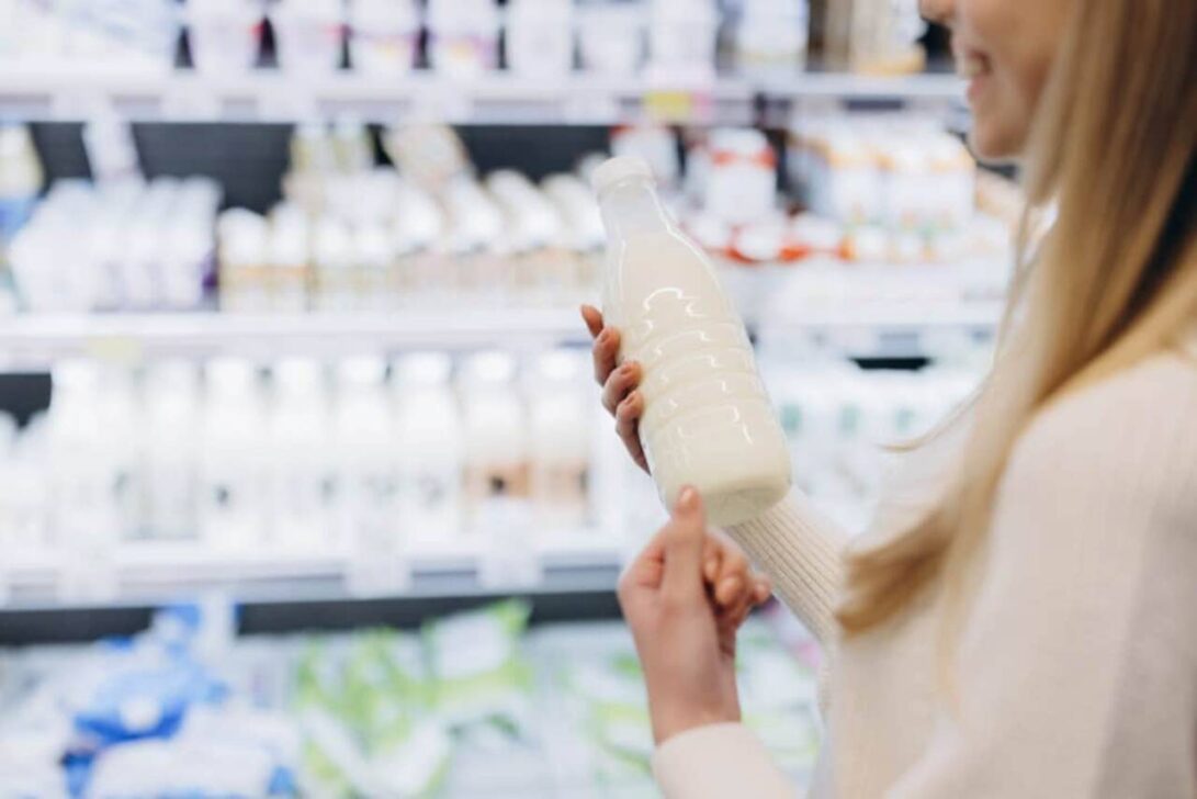 Mulher segurando garrafa de leite enquanto faz compras