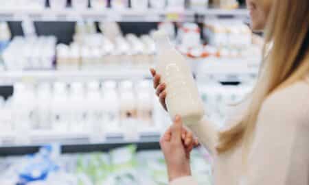 Mulher segurando garrafa de leite enquanto faz compras