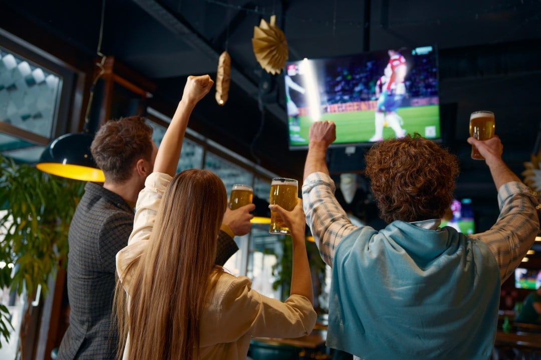Pessoas no bar assistindo jogo de futebol