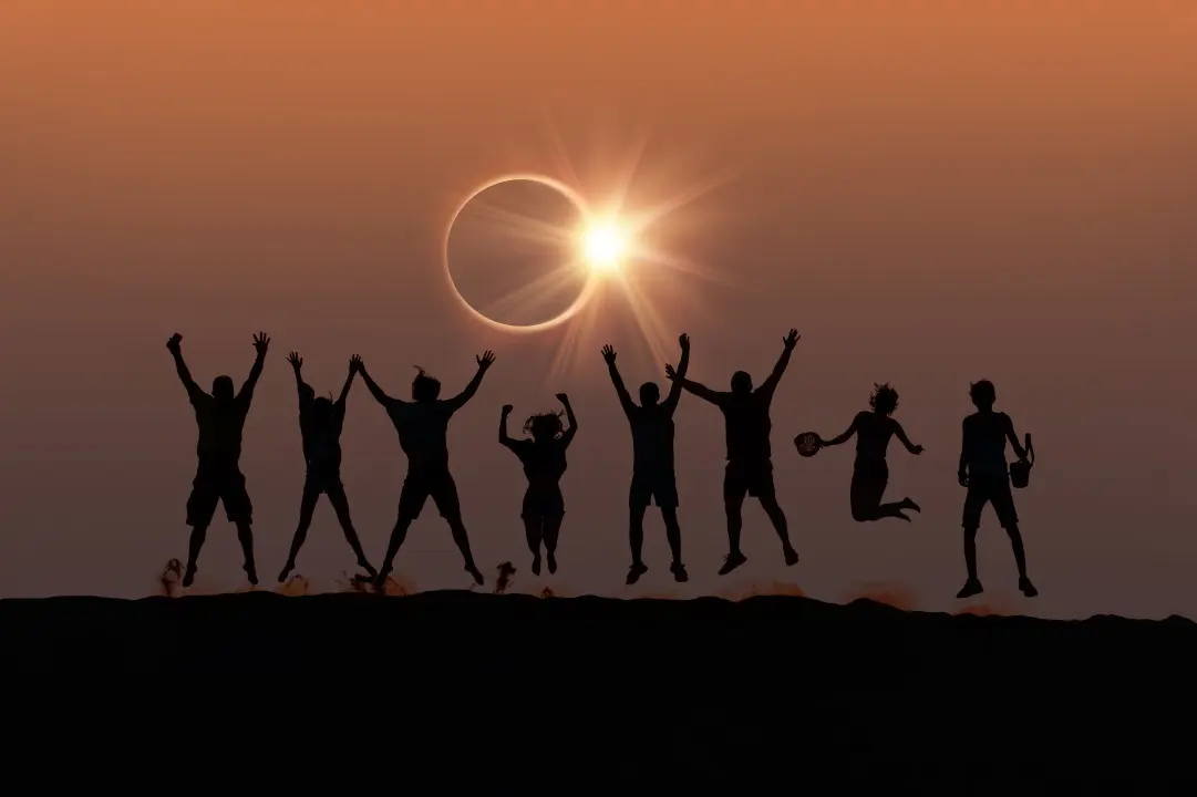 Amigos pulando observando eclipse solar total
