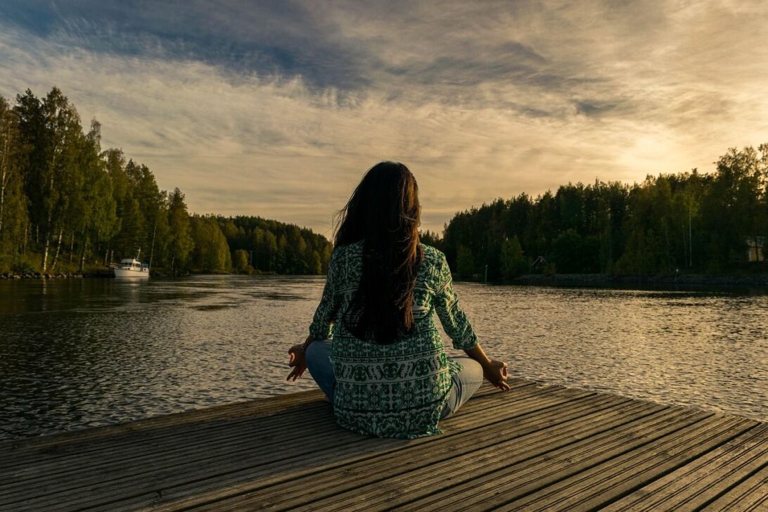 Mulher meditando lago
