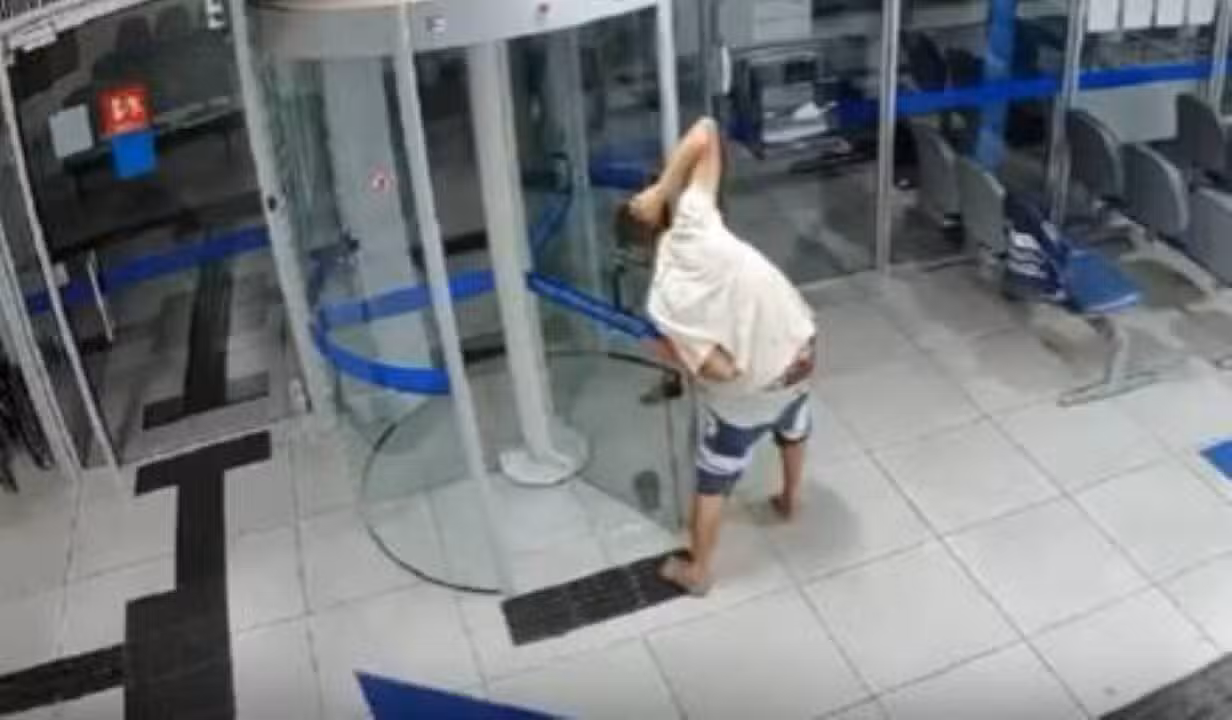 Ladrao fica preso na porta giratória do banco