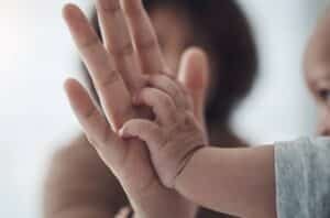 Mãe de mãos dadas com o bebê