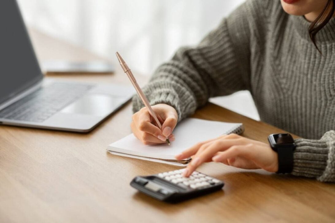 Mulher com calculadora e notebook, cálculos