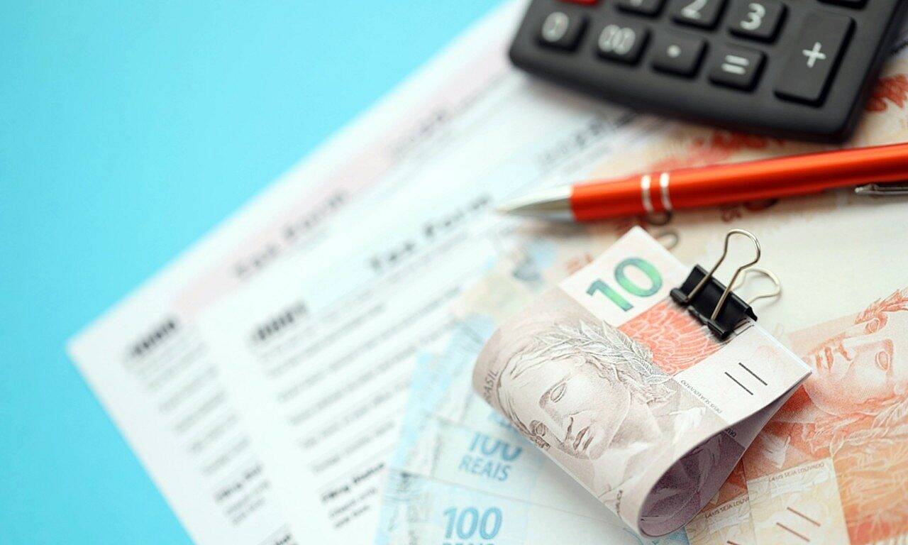 Notas de real, dinheiro, calculadora e forma de imposto - Mehaniq/Shutterstock.com