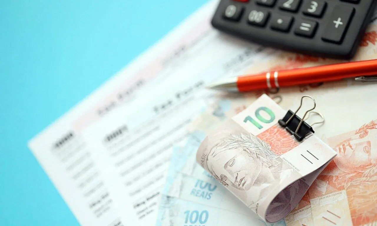 Notas de real, dinheiro, calculadora e forma de imposto - Mehaniq/Shutterstock.com