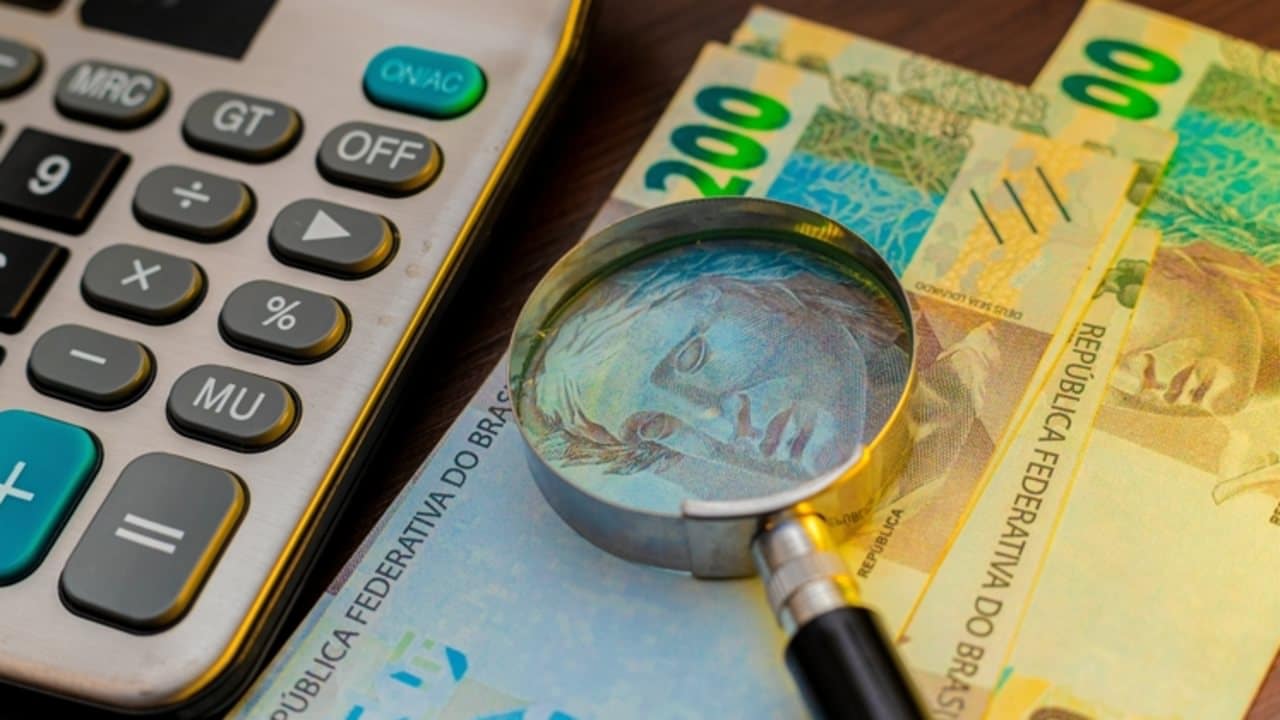 Dinheiro, real, lupa, calculadora - RODWORKS/shutterstock.com
