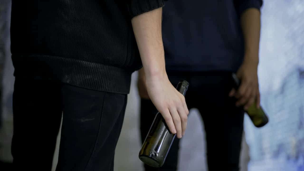 Jovens segurando garrafa. bebida alcóolica - Motortion Films/shutterstock.com