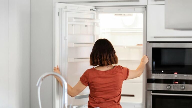 Geladeira aberta com prateleiras e compartimentos internos à vista na cozinha.